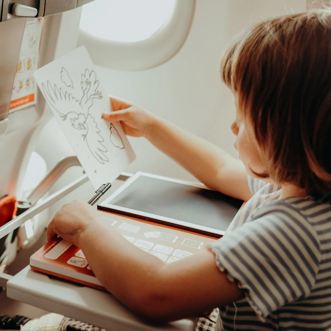 Child using a sewing machine with a tablet on a table