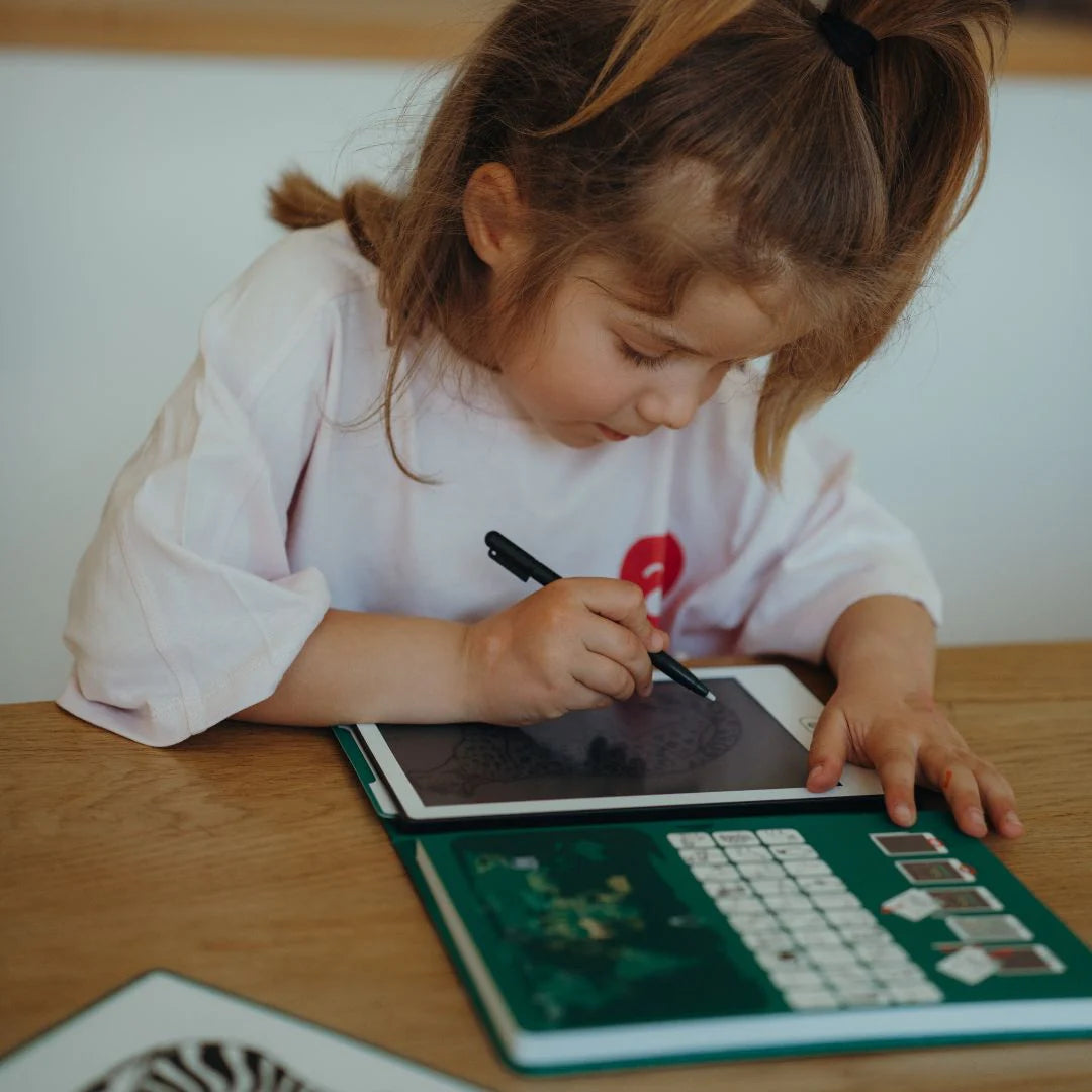 Child using a digital tablet with a stylus on a wooden table.
