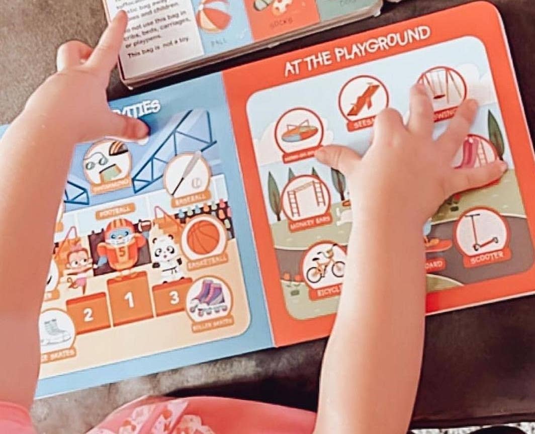 Child's hands interacting with a colorful educational book about playground activities.