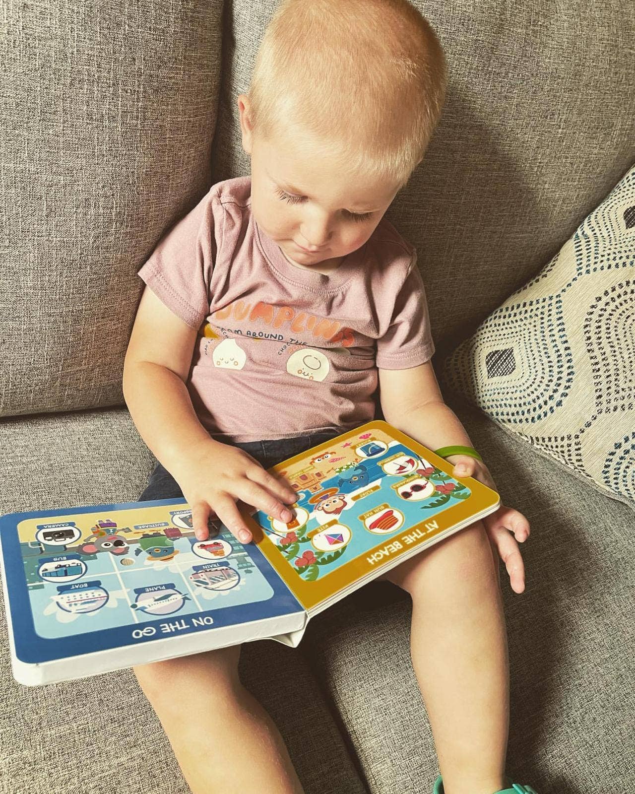 Child sitting on a couch reading a colorful book