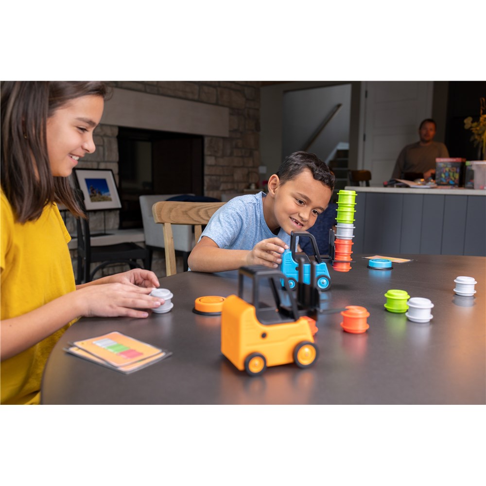 Two children playing with colorful toy blocks on a table in a home setting.