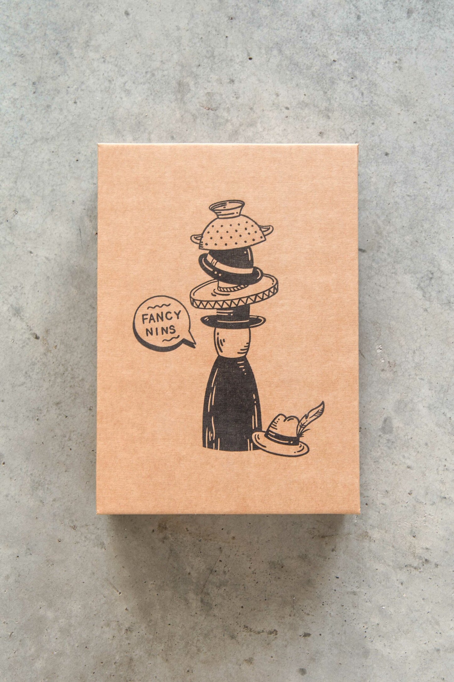 Kraft paper box with black illustration and text on a gray concrete surface