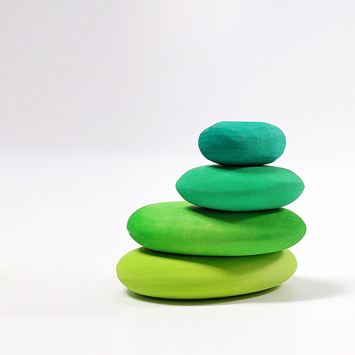 Stack of green wooden stones on a white background