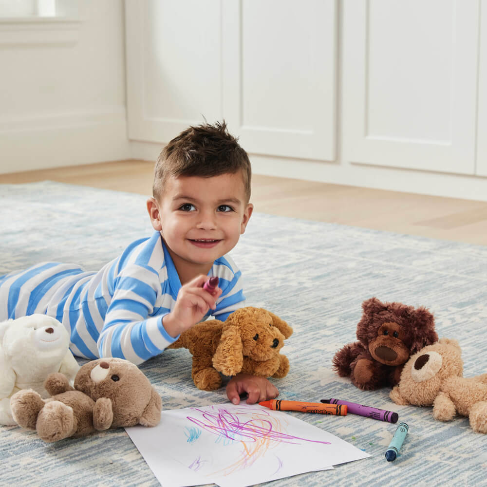 Child playing with stuffed animals and drawing on a rug