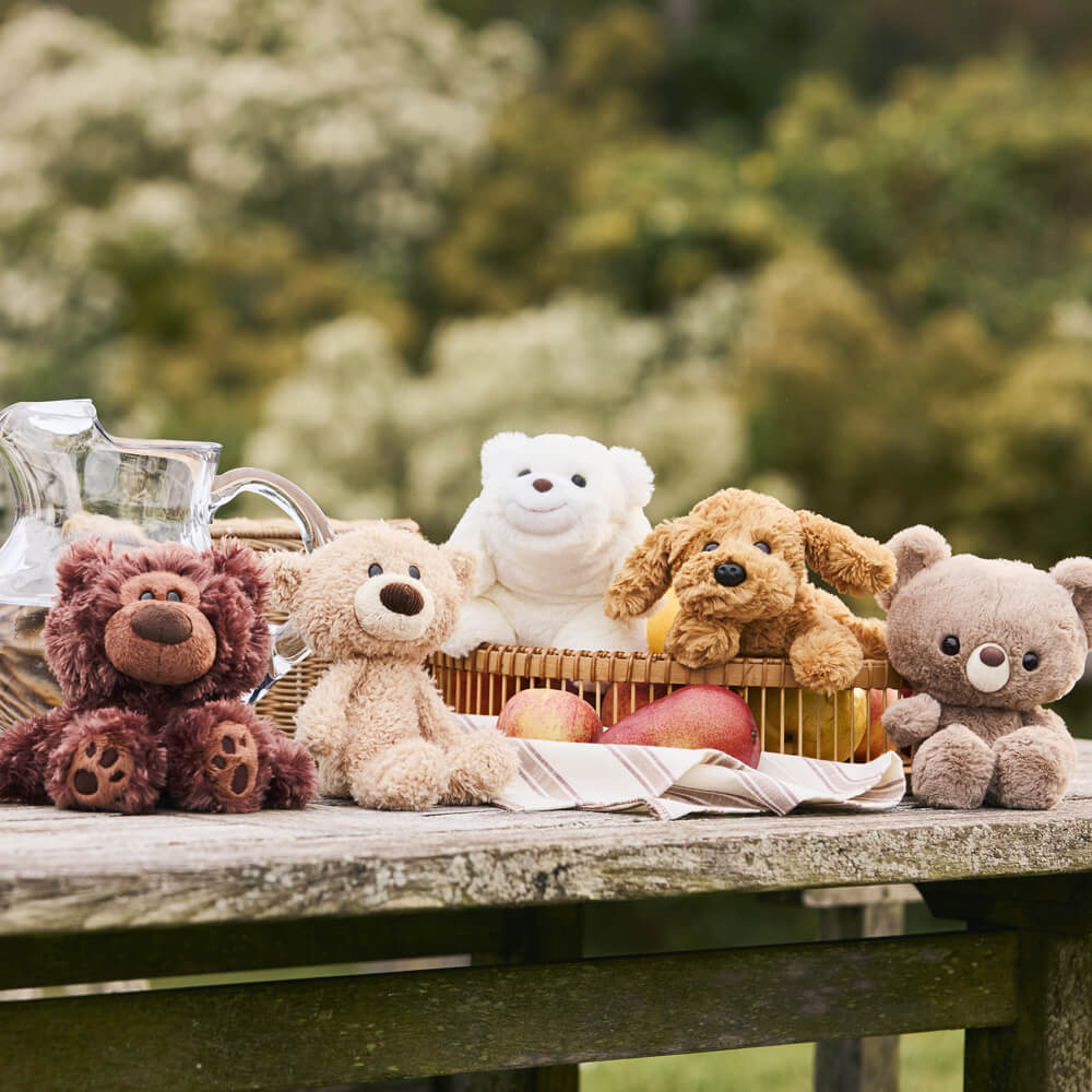 Stuffed animals on a wooden table with a blurred natural background