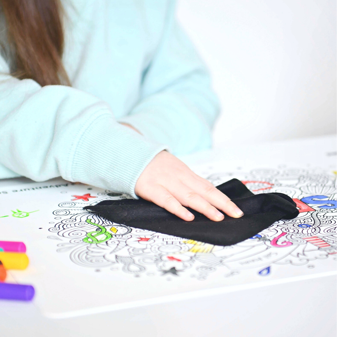 Child using black cloth on reusable colouring mat.