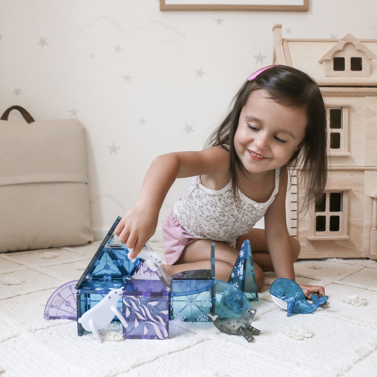 Child playing with magnetic tiles and arctic animals on a bedroom setting.