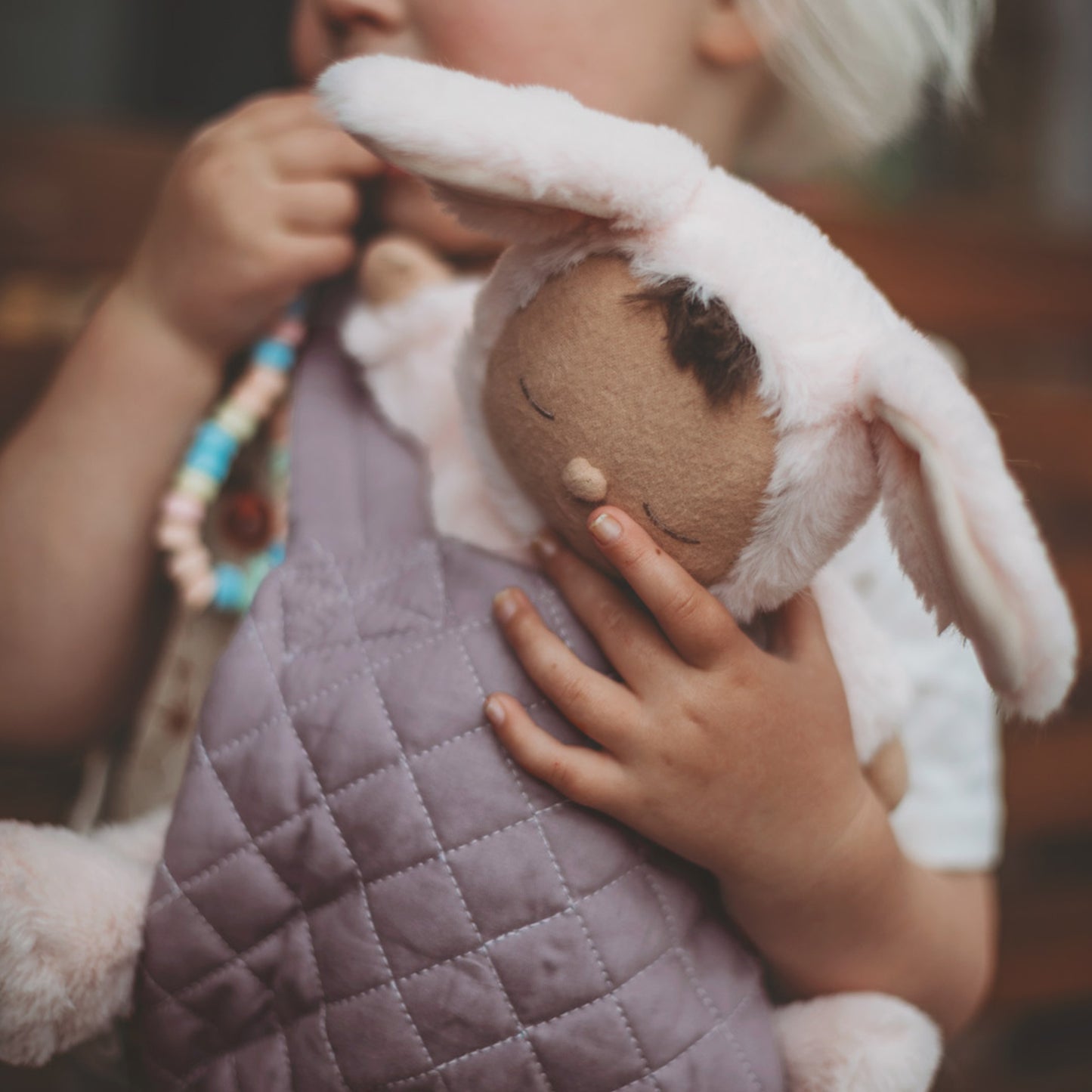 Child holding a plush toy with a blurred background