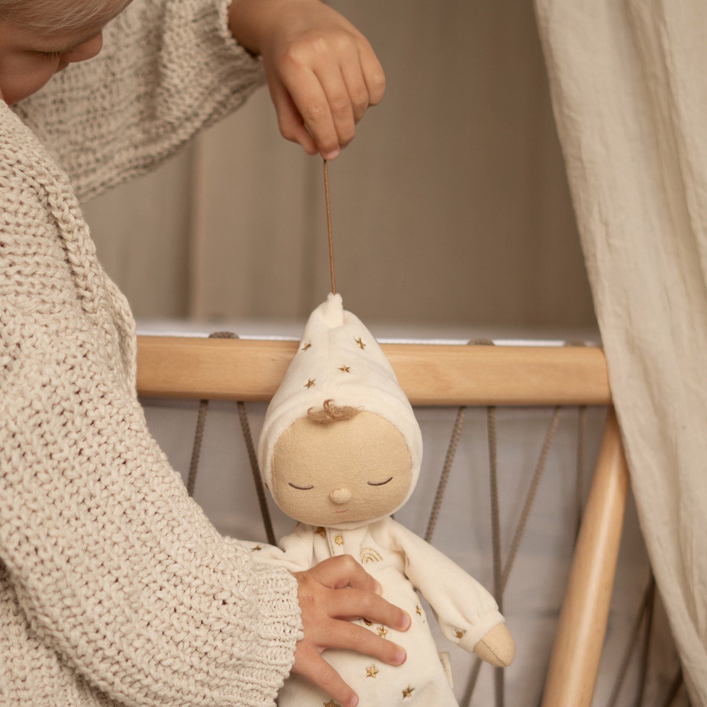 Child holding a small white doll with a neutral background