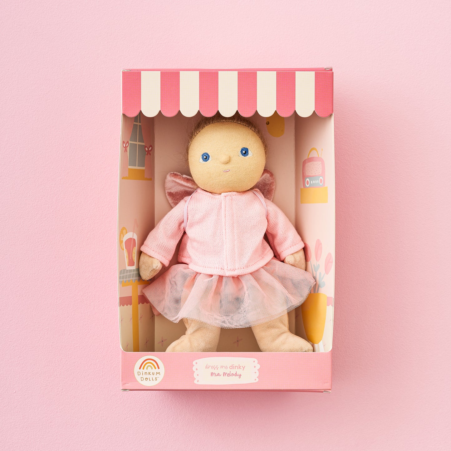 Toy doll in a pink dress with a toy bottle and pacifier in a decorative box on a pink background