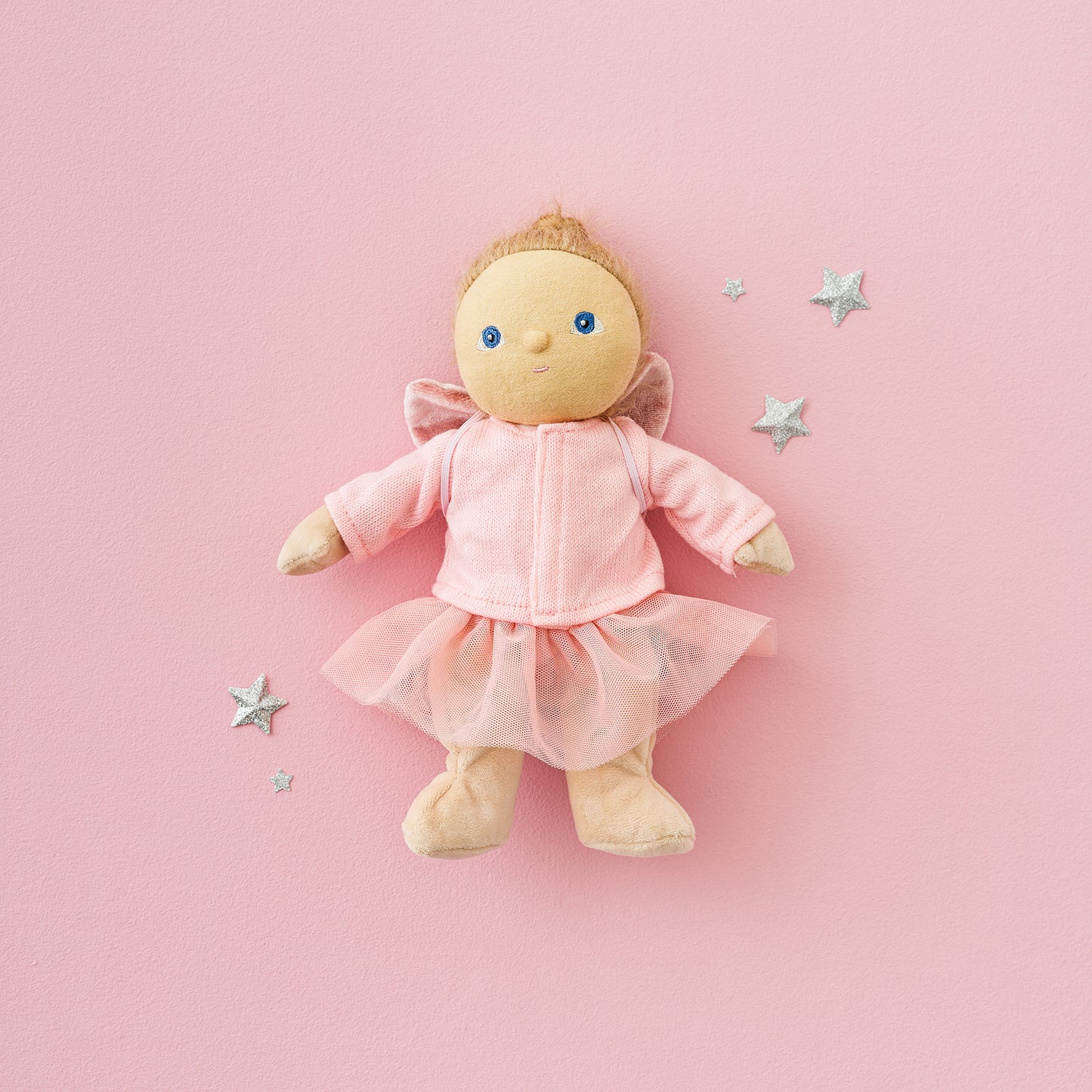 Stuffed doll in a pink outfit on a pink background with decorative stars.