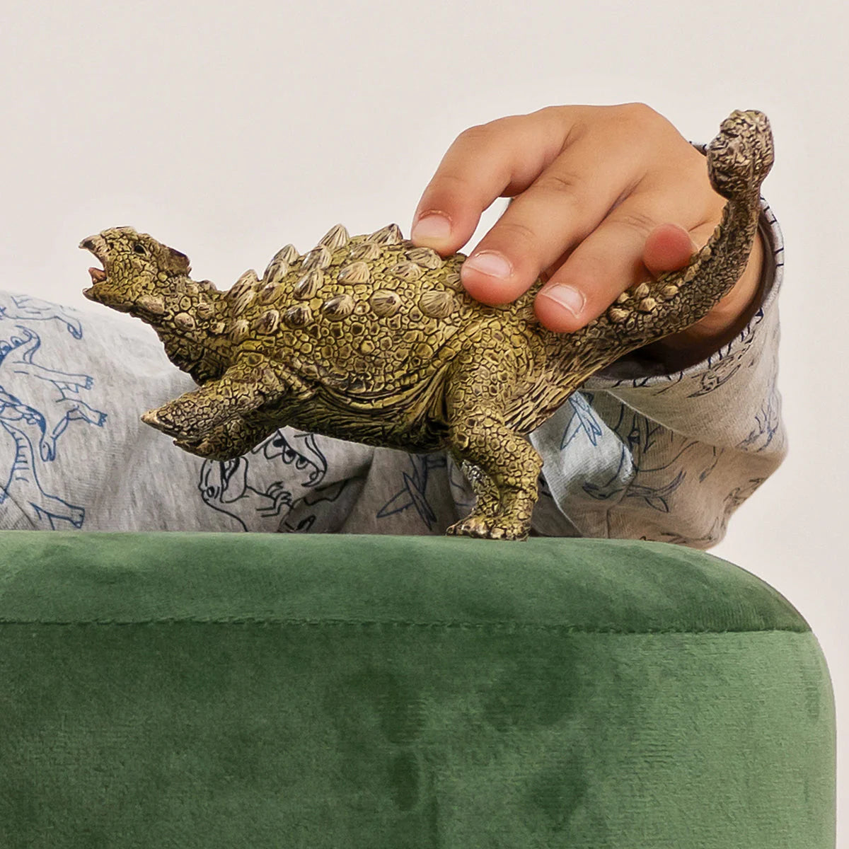 Hand holding a detailed turtle figurine on a green surface with a neutral background