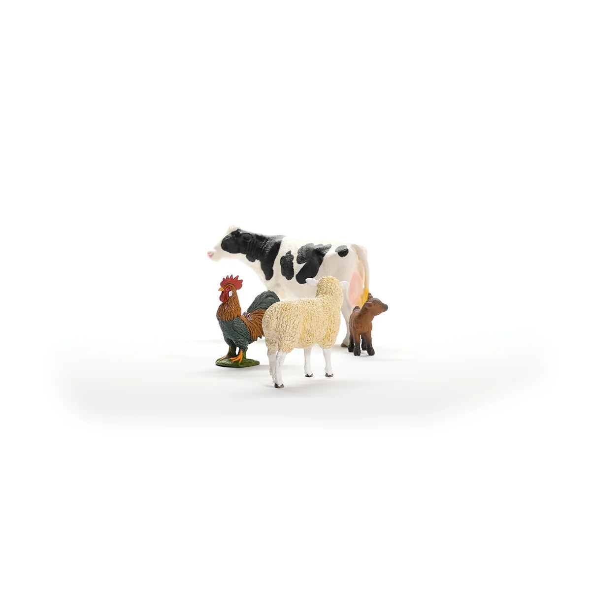 Set of toy farm animals including a cow, rooster, and sheep on a white background
