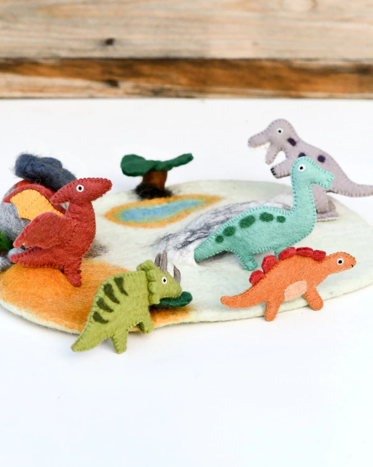 Colorful dinosaur toys on a white surface with a wooden background