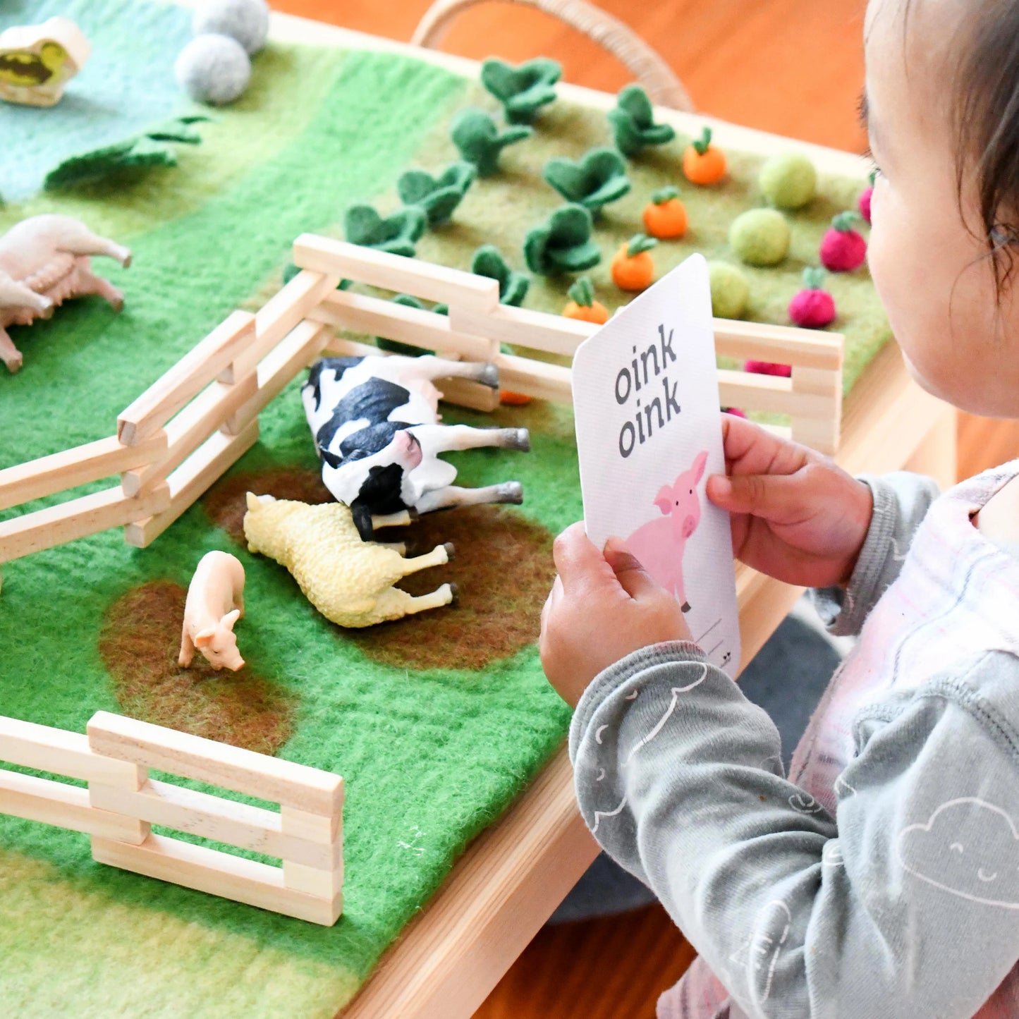 Child playing with a farm-themed toy set on a felt play mat