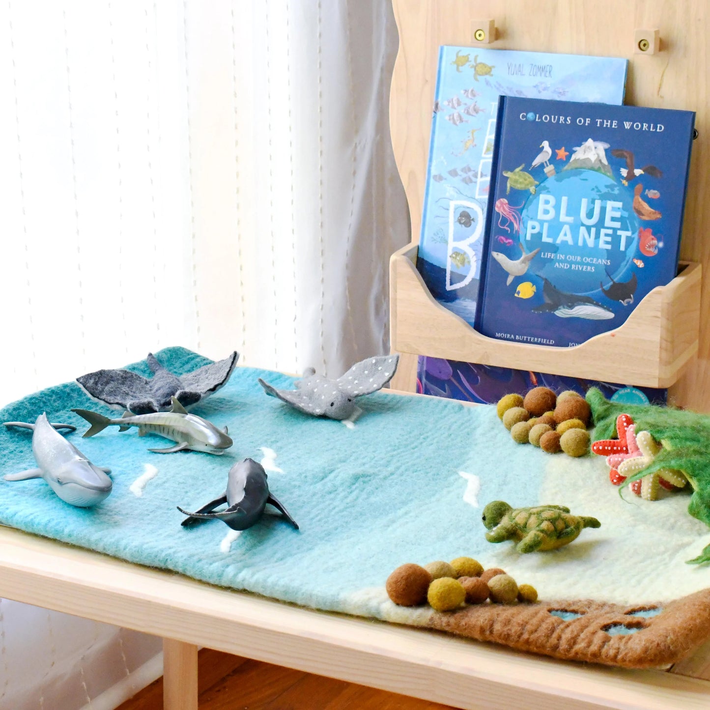 Children's educational setup with toy whales, turtle, and books on a table.