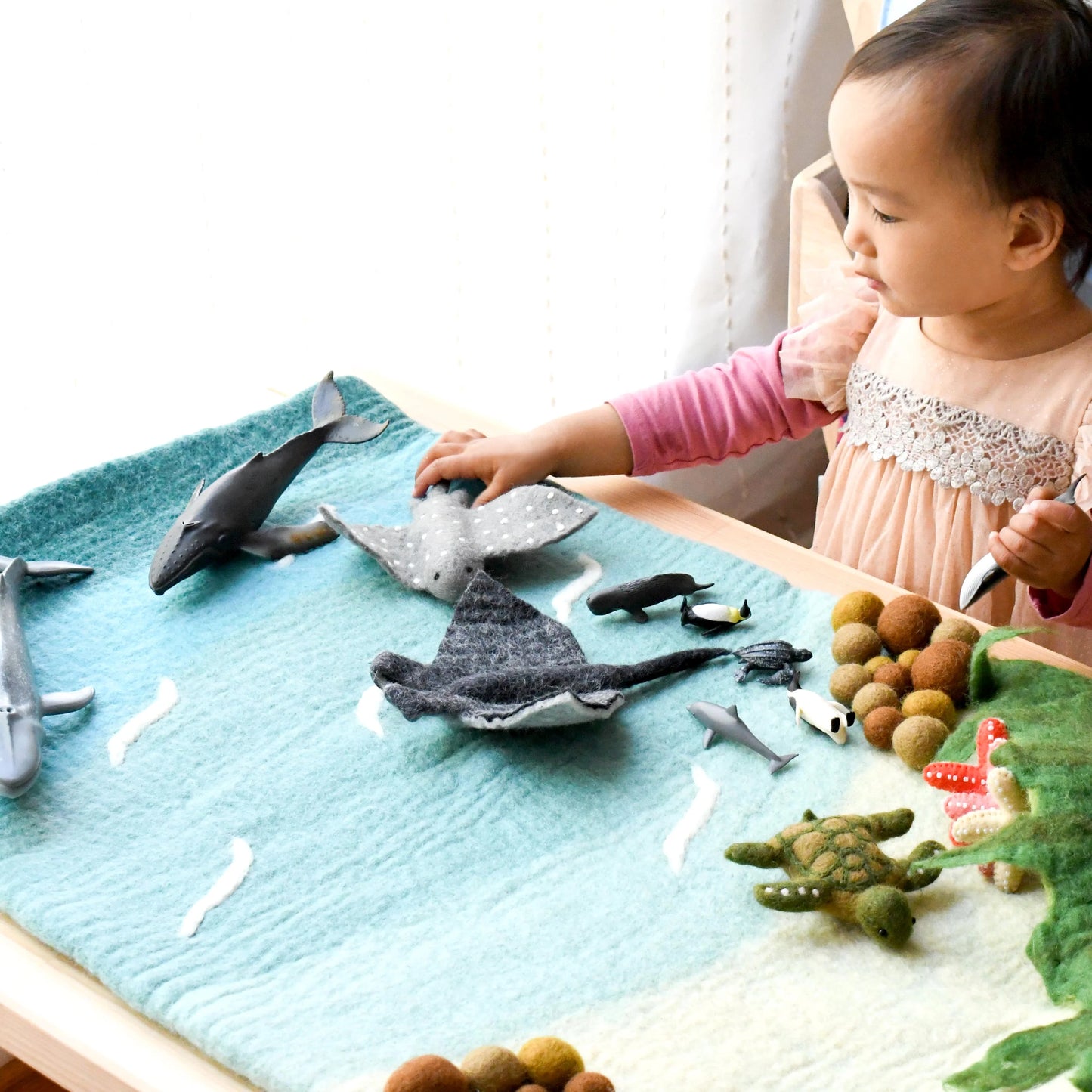 Child playing with felt sea creature toys on a table