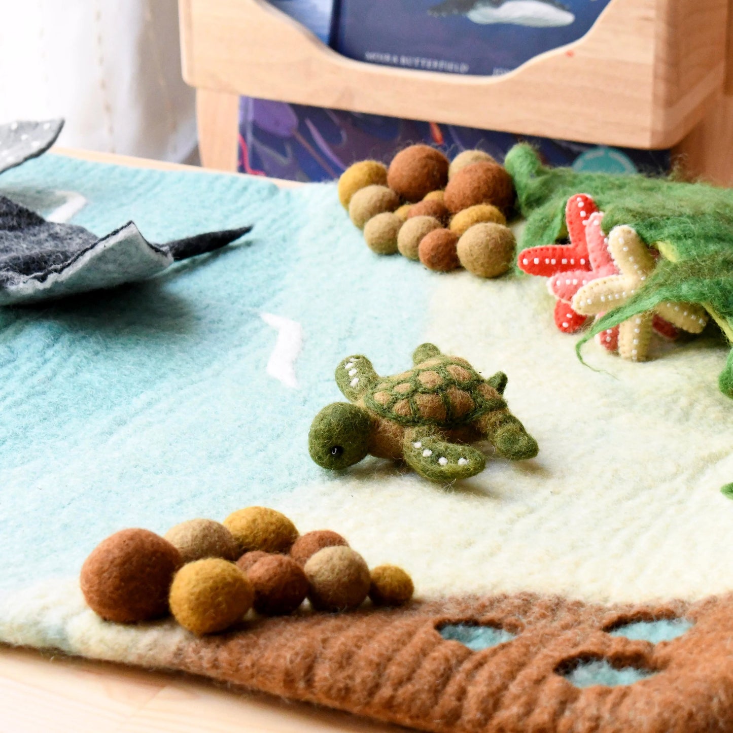 Felted sea turtle and coral on a textured surface with a blurred background