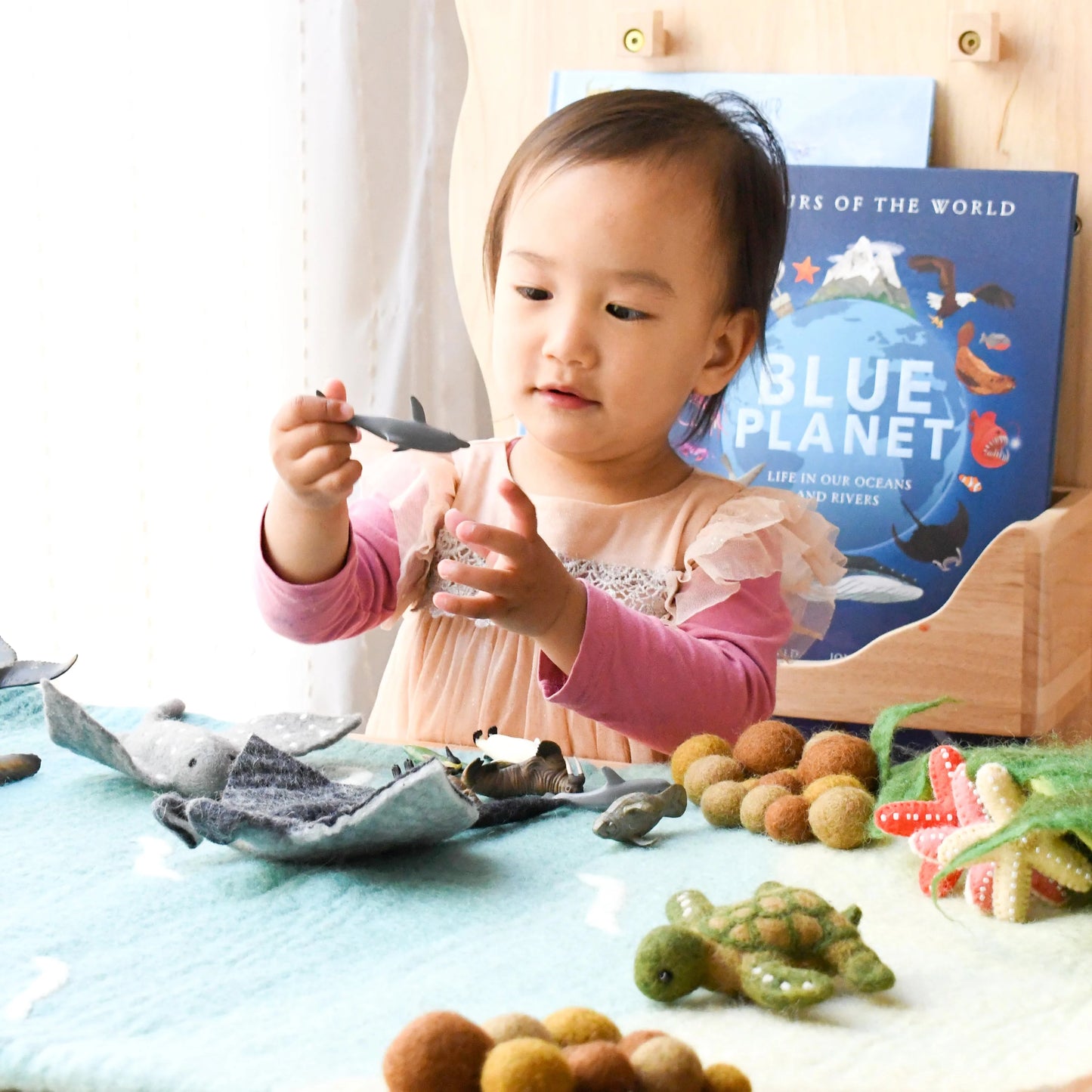 Child playing with educational toys and books on a table