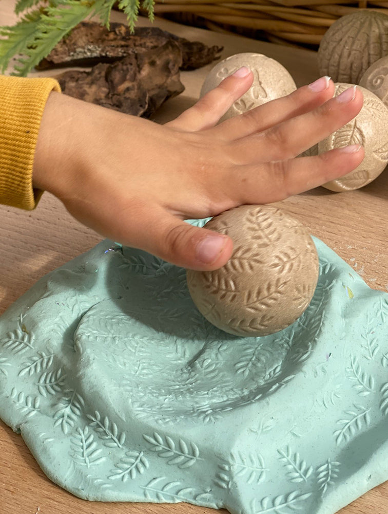 Hand interacting with a textured stone ball on a green surface