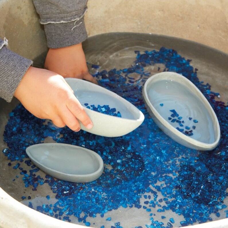 Child playing with blue beads in a tray using gray molds.