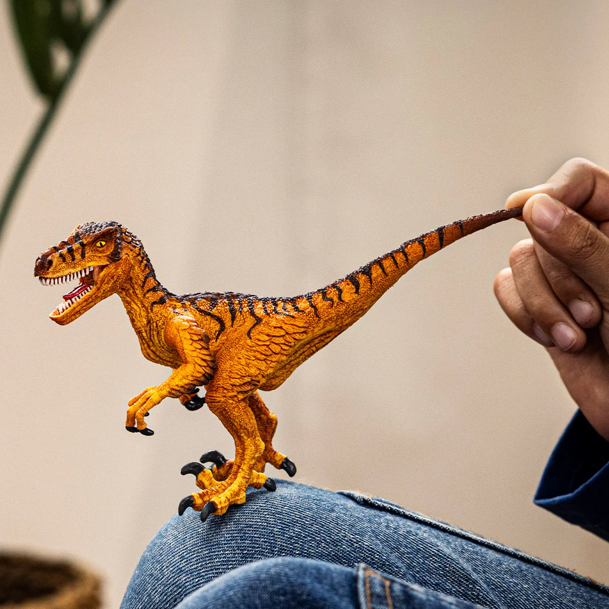Toy dinosaur being held by a person on a neutral background