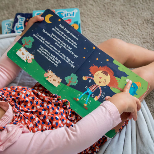 Child reading a colorful children's book with illustrations of a boy and a dog.