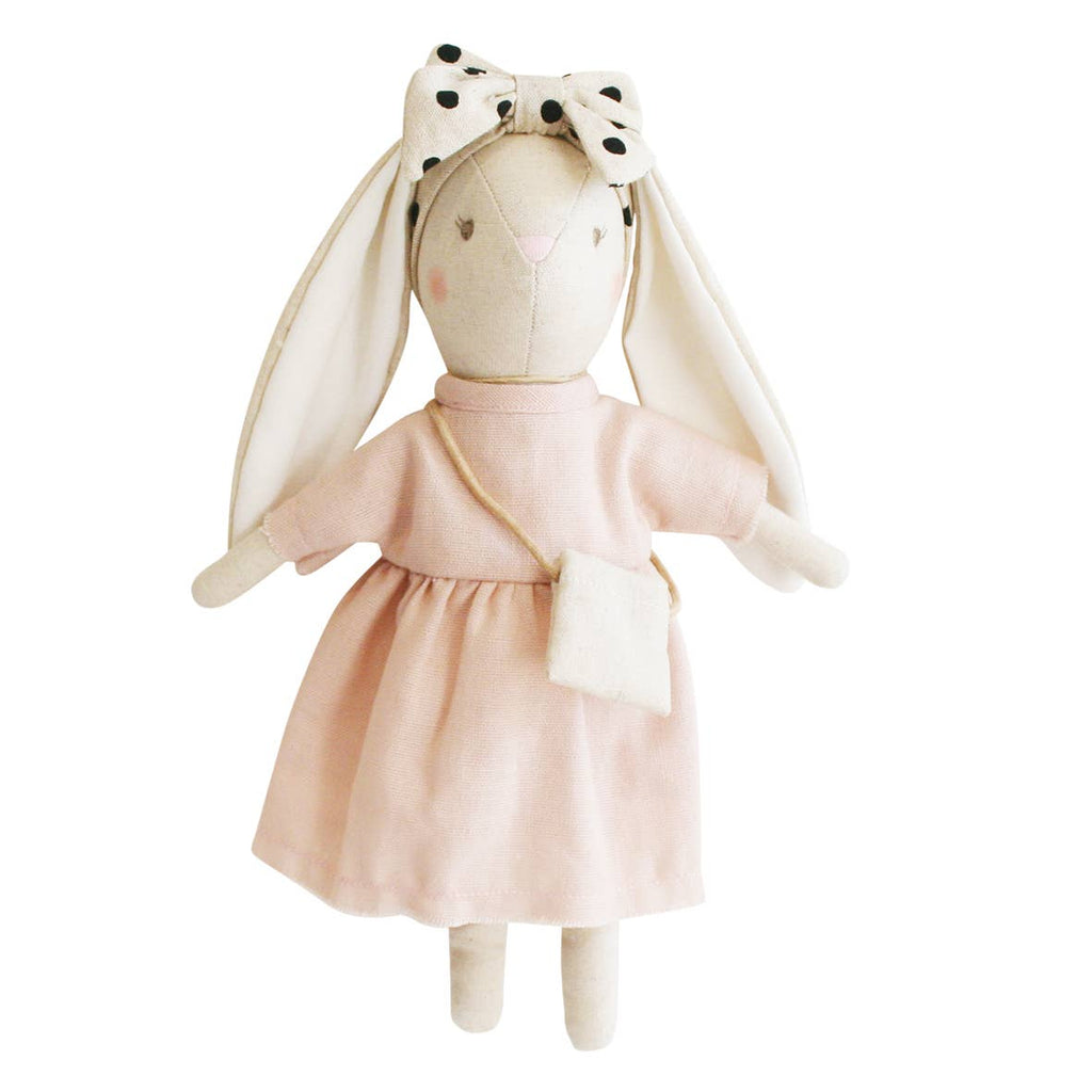 Stuffed toy rabbit in a pink dress with a white bow on a white background