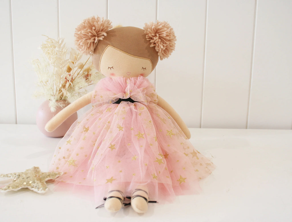 Stuffed doll with a pink dress and brown hair bun on a white background