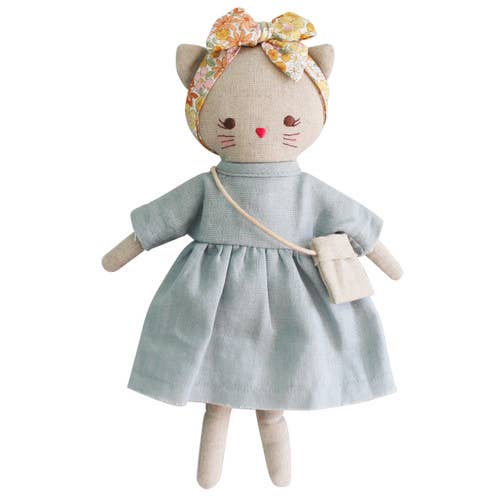 A small doll designed to look like a kitten, with a grey linen dress, a floral headband, and a small bag.