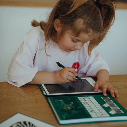 Child using a digital tablet with a stylus on a wooden table.