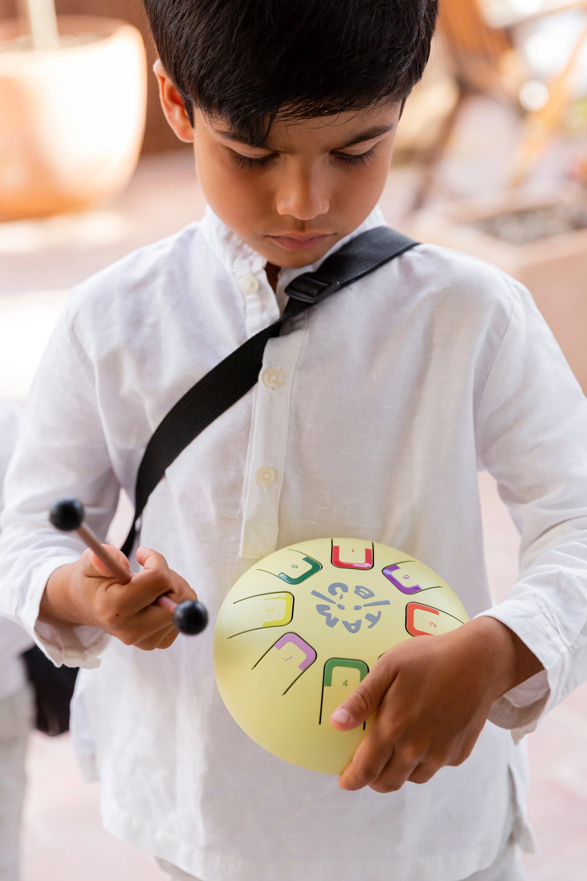 Child playing a colorful handbell outdoors