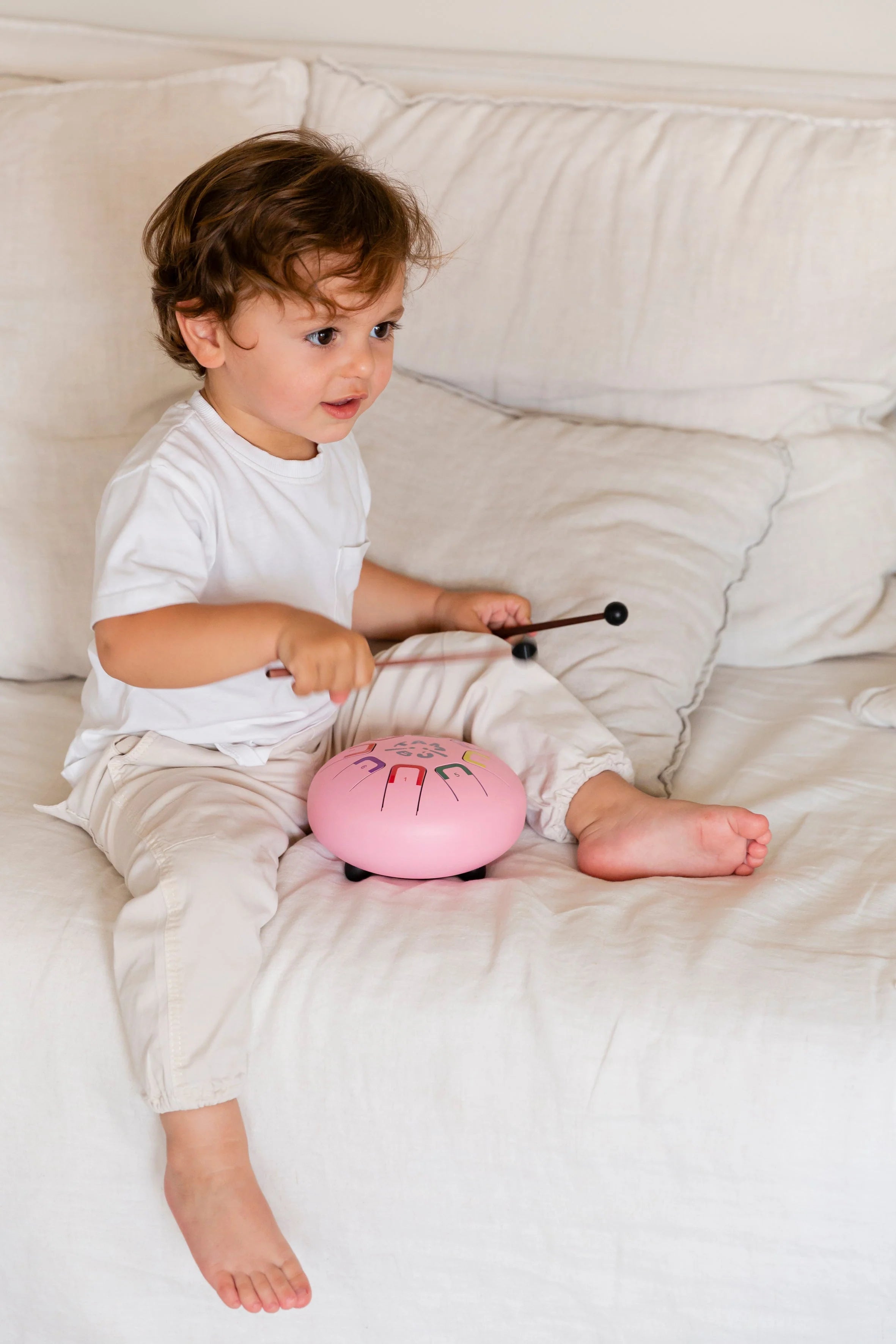 Child playing with a pink toy on a bed