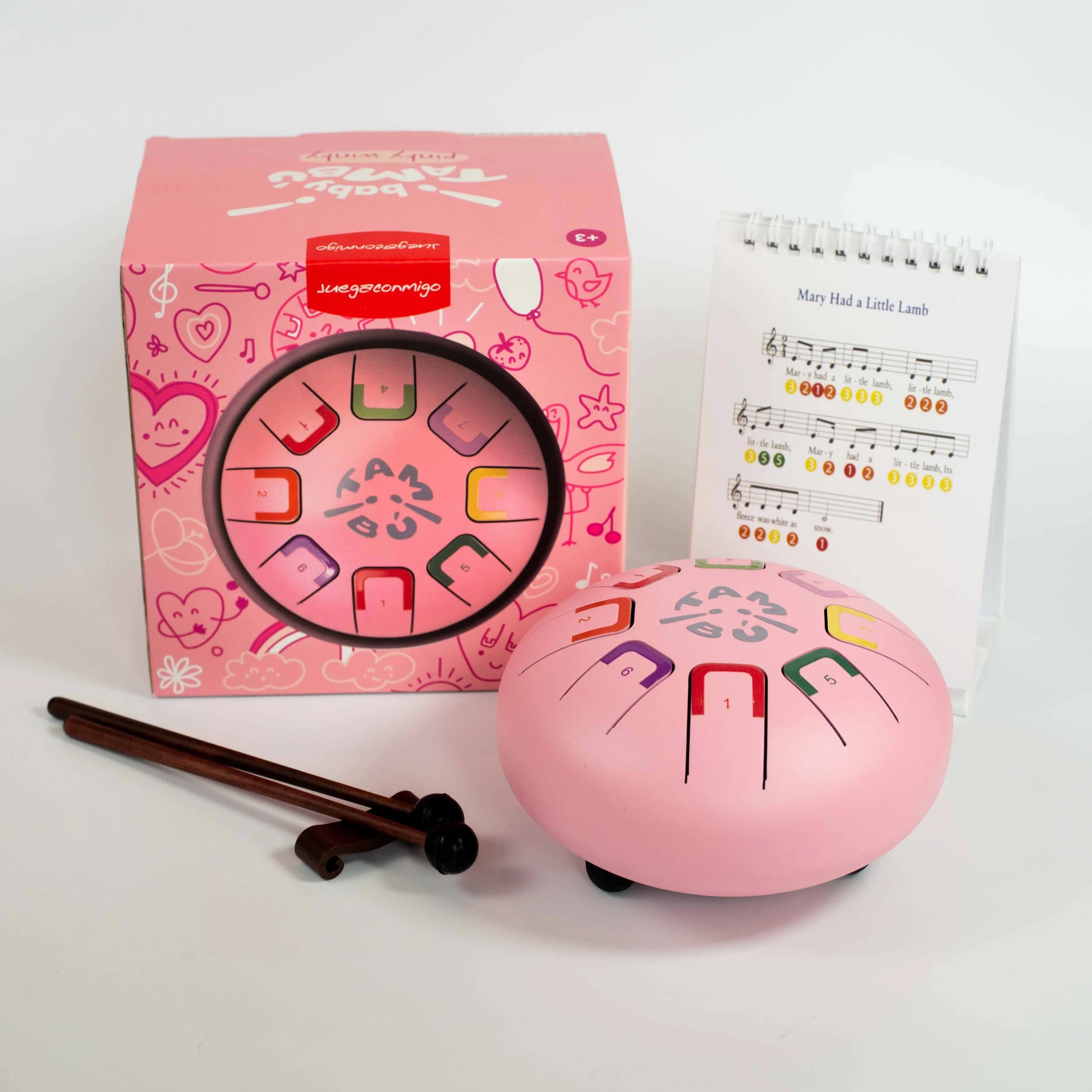 Pink musical instrument with colorful keys, packaging, and music sheet on a white background