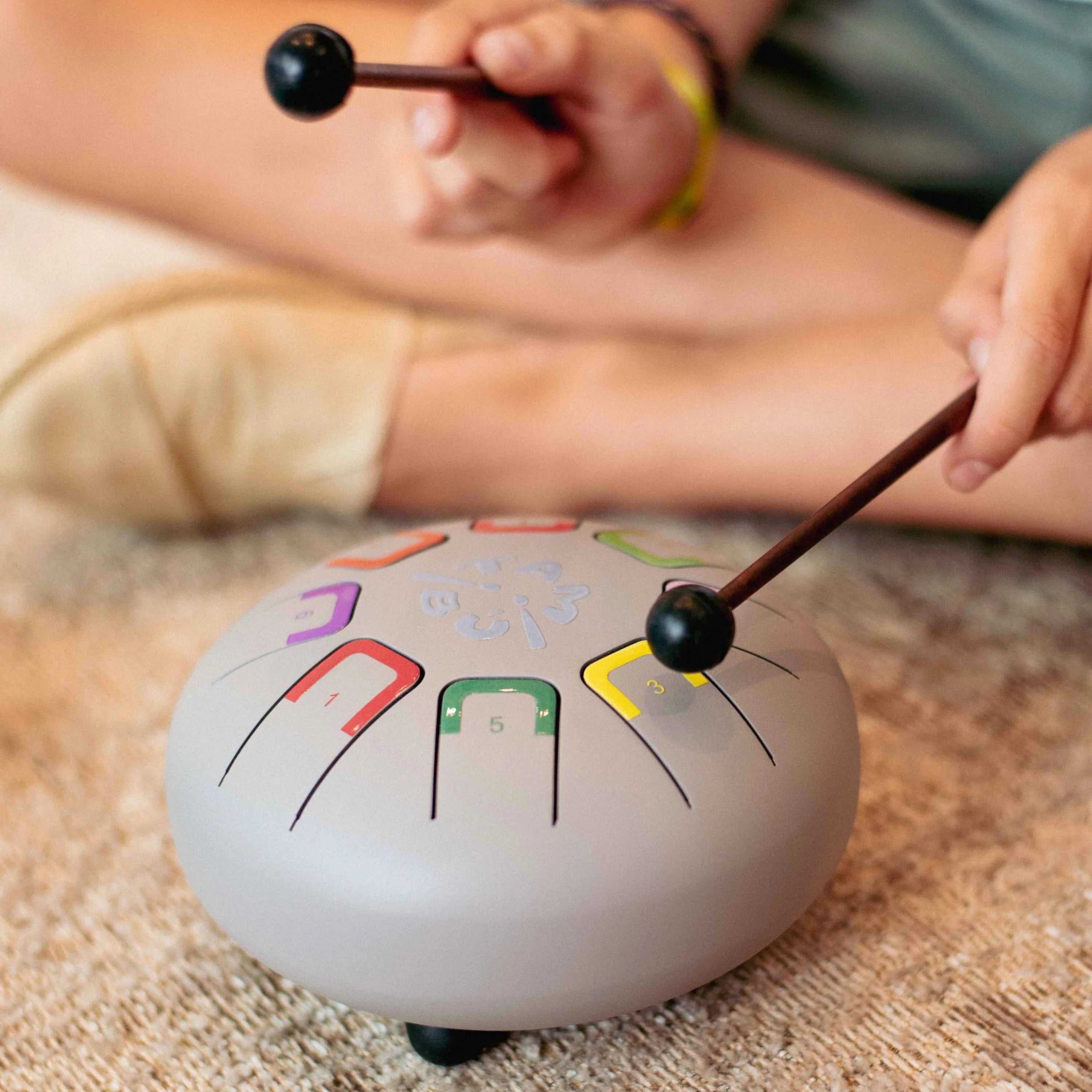 Person playing a gong with musical notes on a carpeted floor