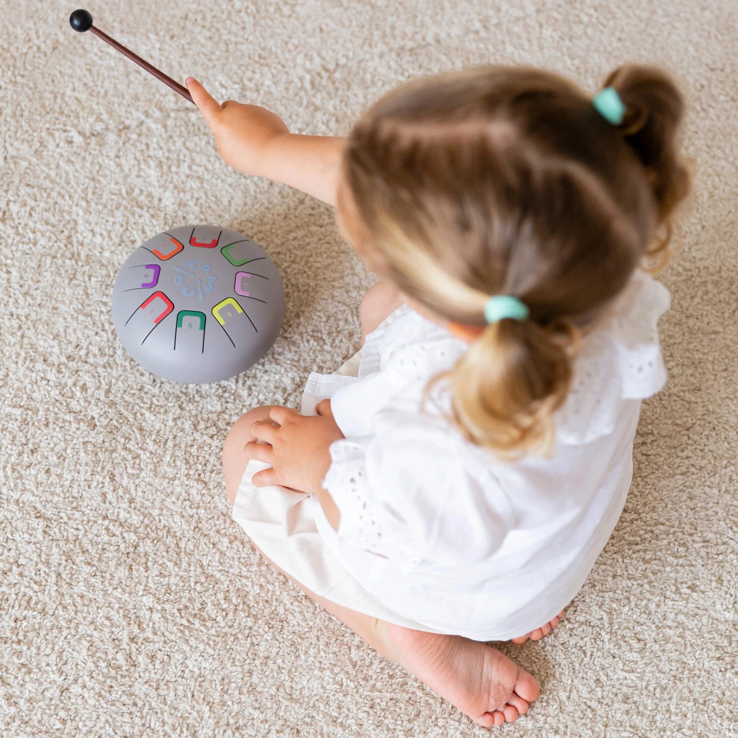 Child playing with a colorful percussion instrument on a carpeted floor