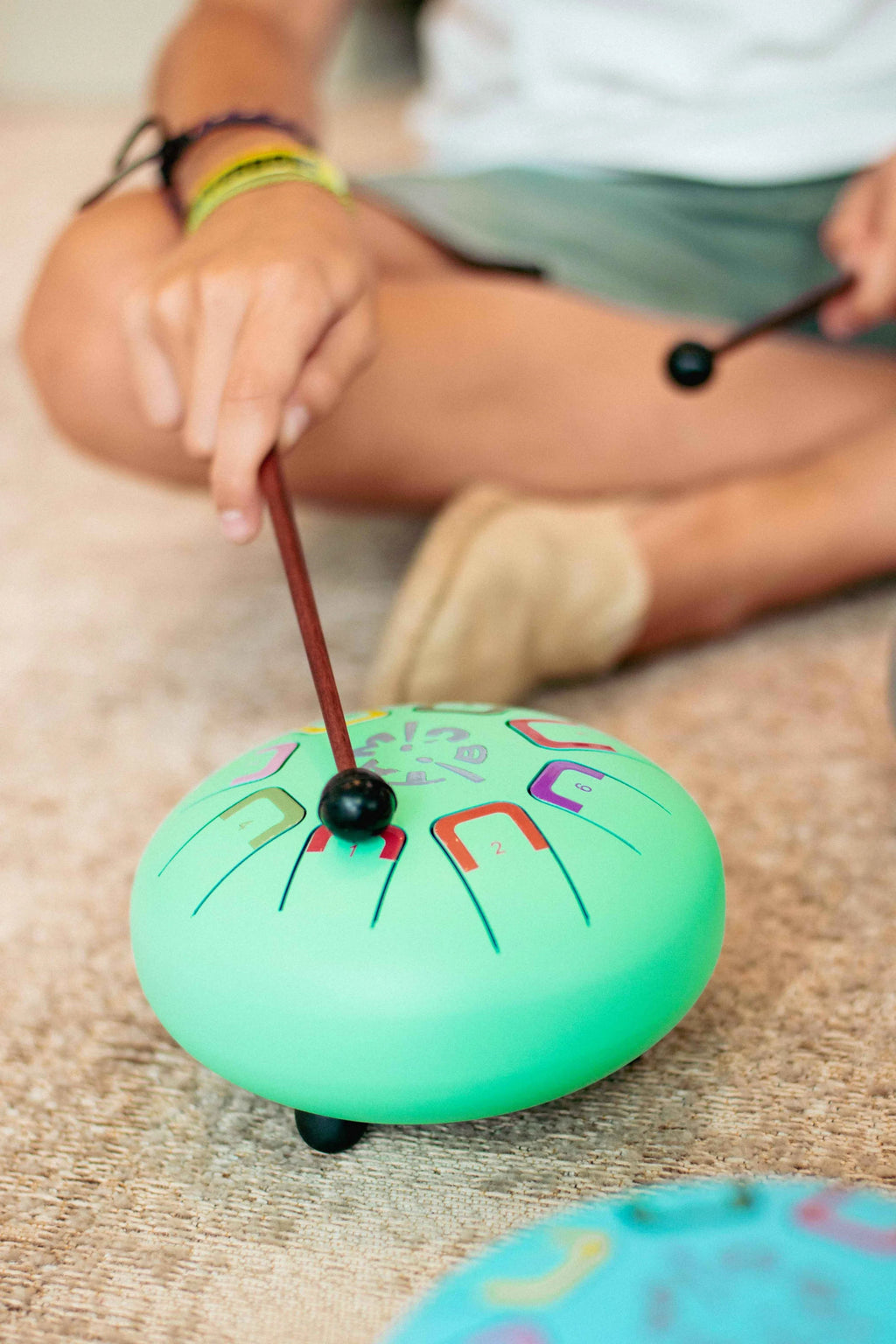Child playing with a colorful hand drum on a carpeted floor