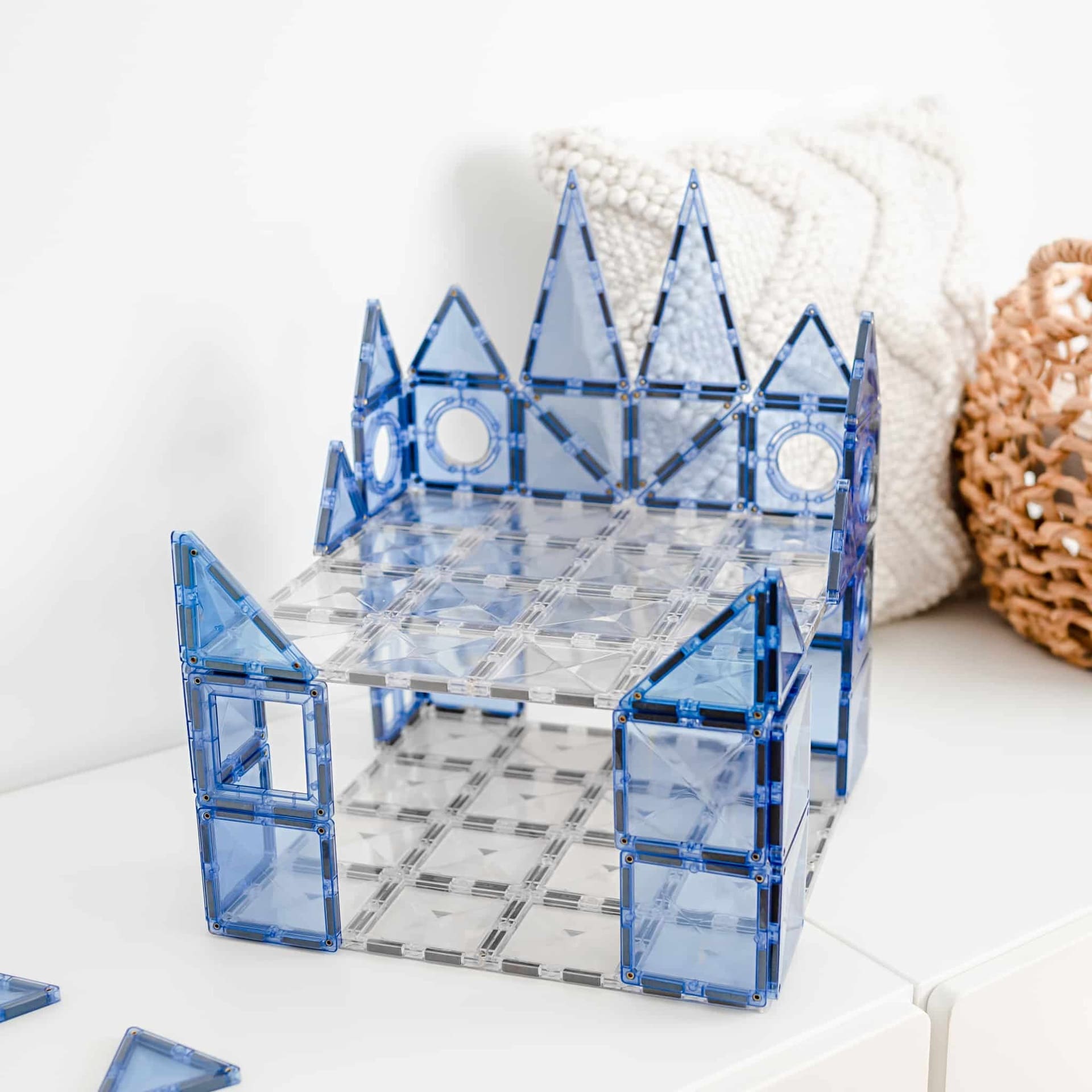 Blue magnetic building blocks forming a castle-like structure on a white surface.