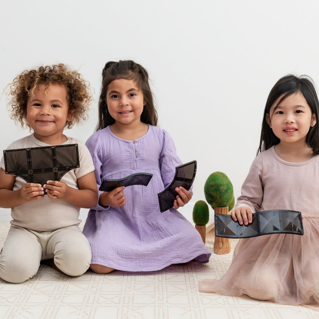 Three children holding black rectangular objects on a white background