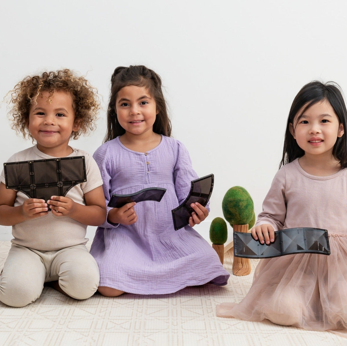 Three children holding black rectangular objects on a white background