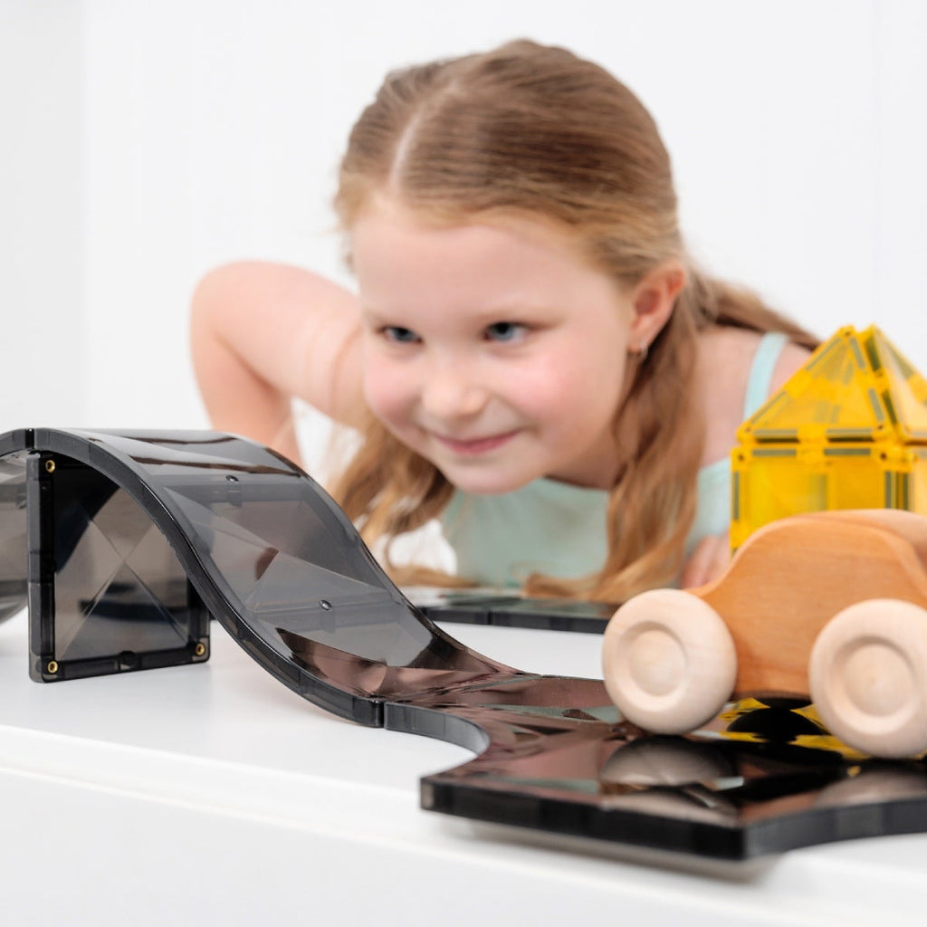 Child playing with a toy car on a track