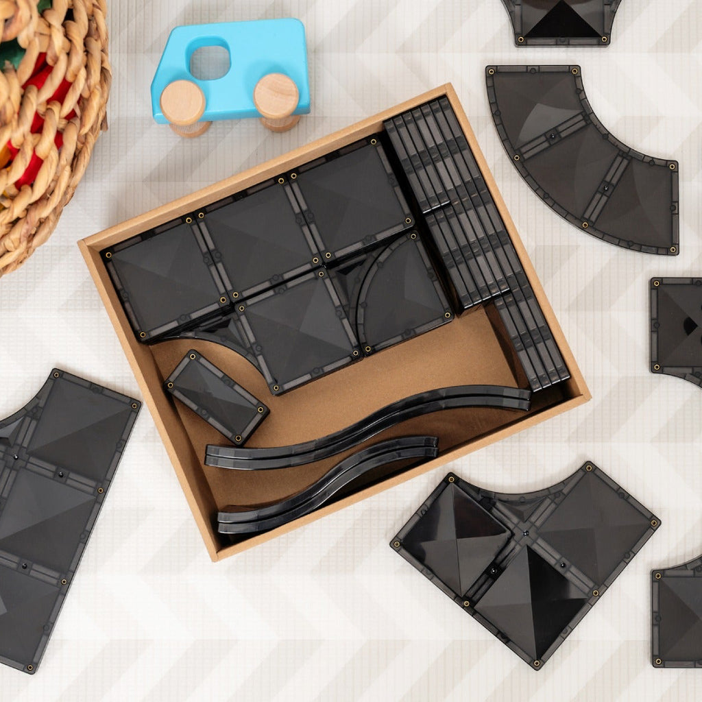 Black geometric building blocks with a wooden box on a light surface.