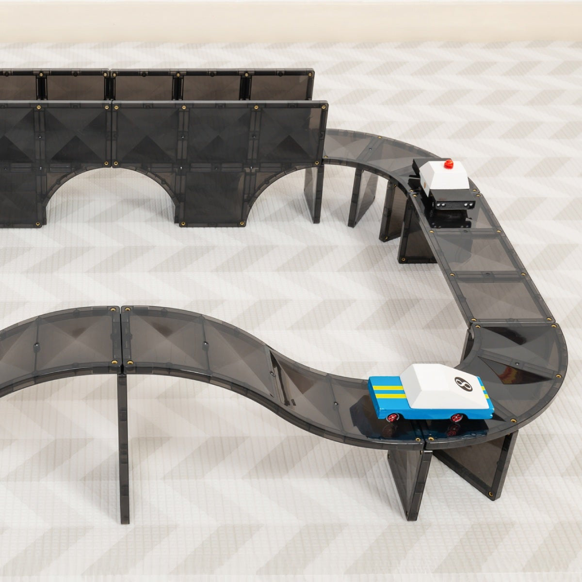 Black toy car track with cars on a light gray background