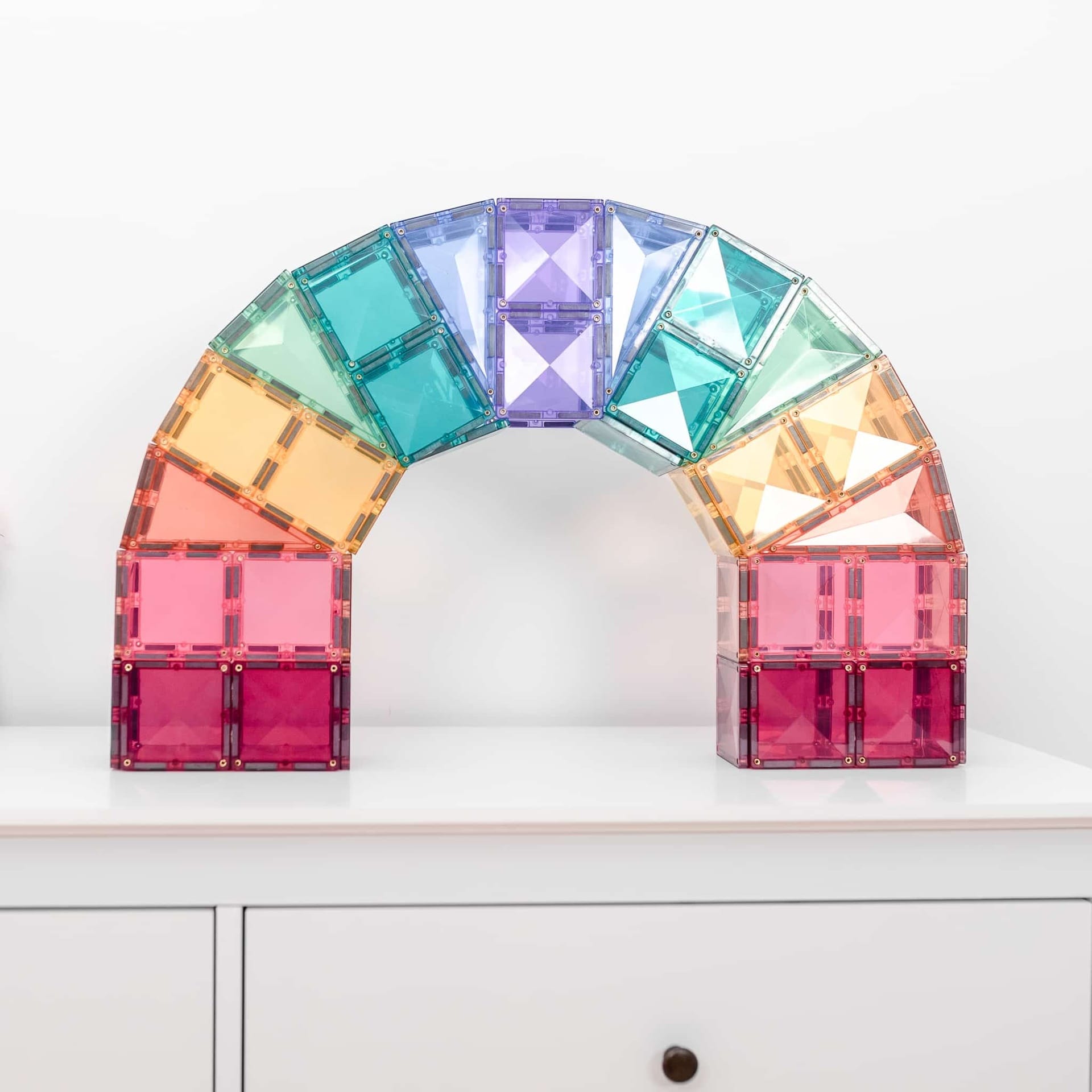 Colorful arch-shaped structure made of interlocking tiles on a white surface.