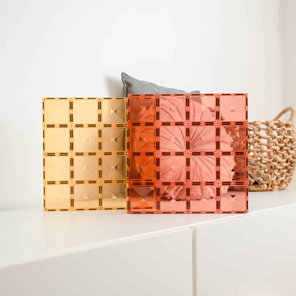 Two decorative boxes, one gold and one pink, on a white surface with a neutral background.