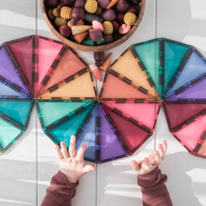 Colorful geometric shapes on a wooden surface with a bowl of candies.