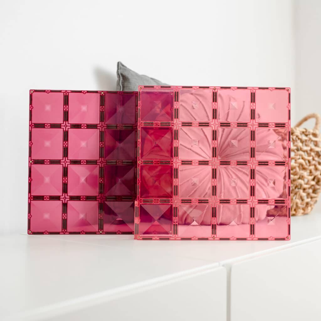 Two pink transparent cosmetic boxes on a white surface with a neutral background
