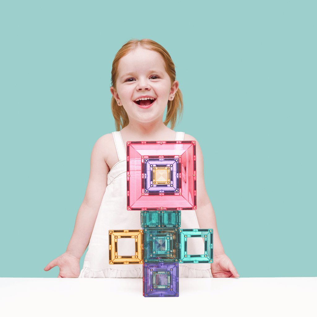 Child holding colorful geometric blocks against a light blue background