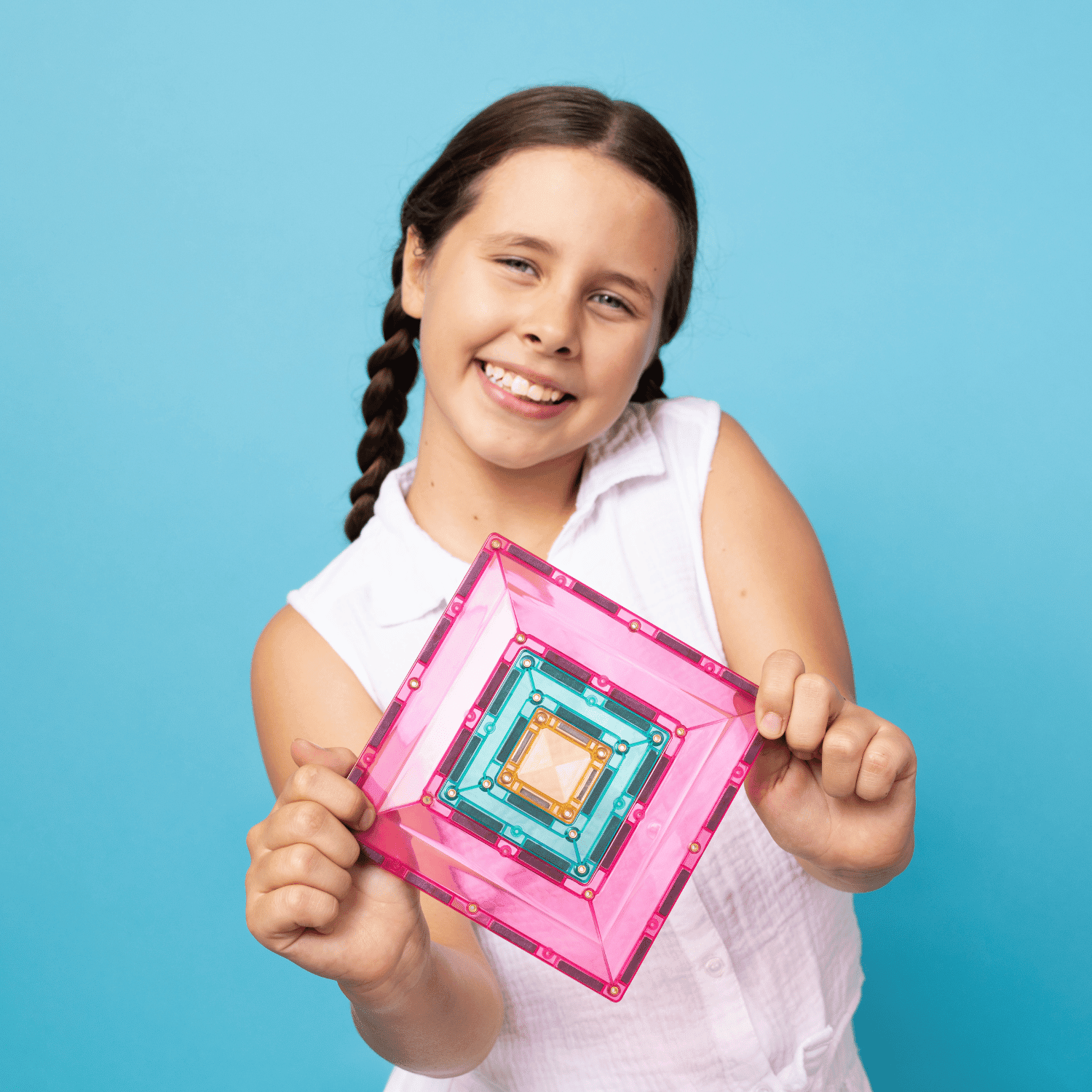 Young girl holding a pink and clear rectangular object against a blue background