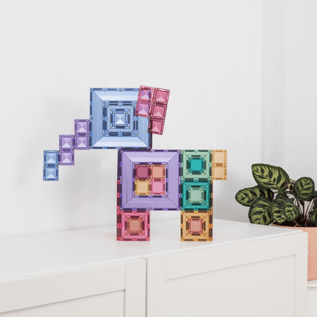 Colorful geometric block set on a white surface with a plant in the background
